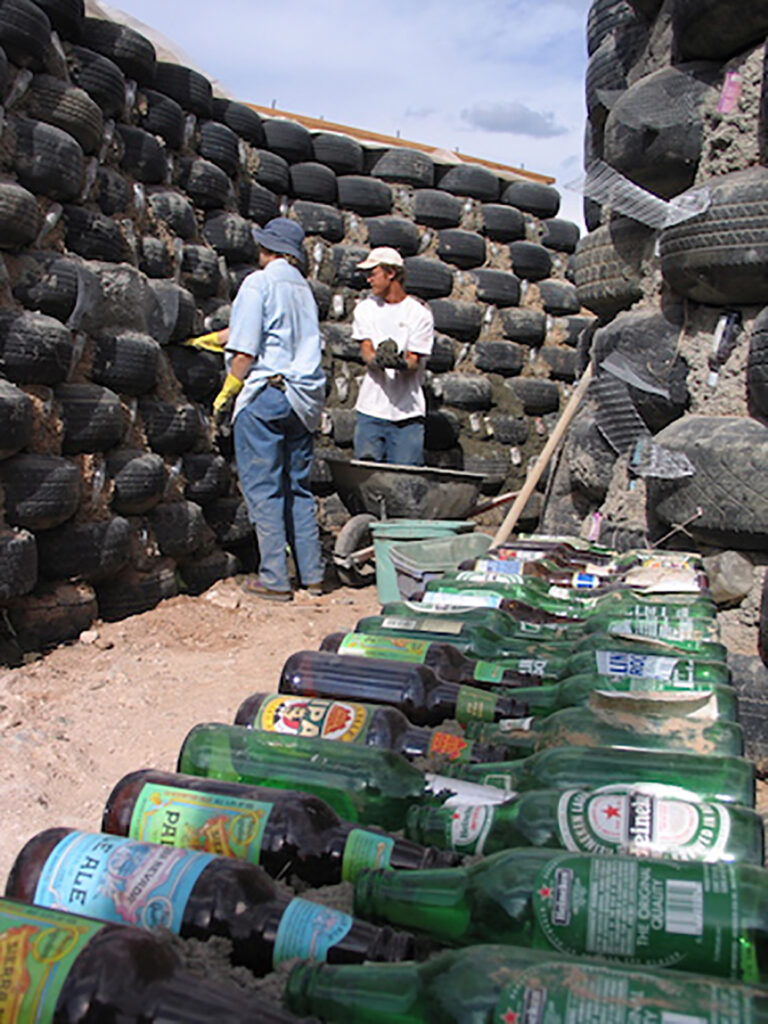 © Earthship biotecture, Changement de paradigme, pneus et bouteille en verre deviennent des éléments de construction